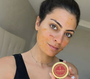Woman with a face mask holding a product labeled 'IYARAA'